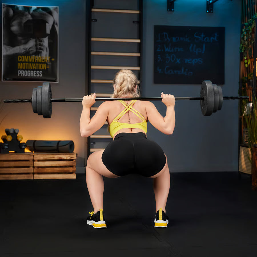 Person performing a barbell squat in a gym setting with motivational posters on the wall.