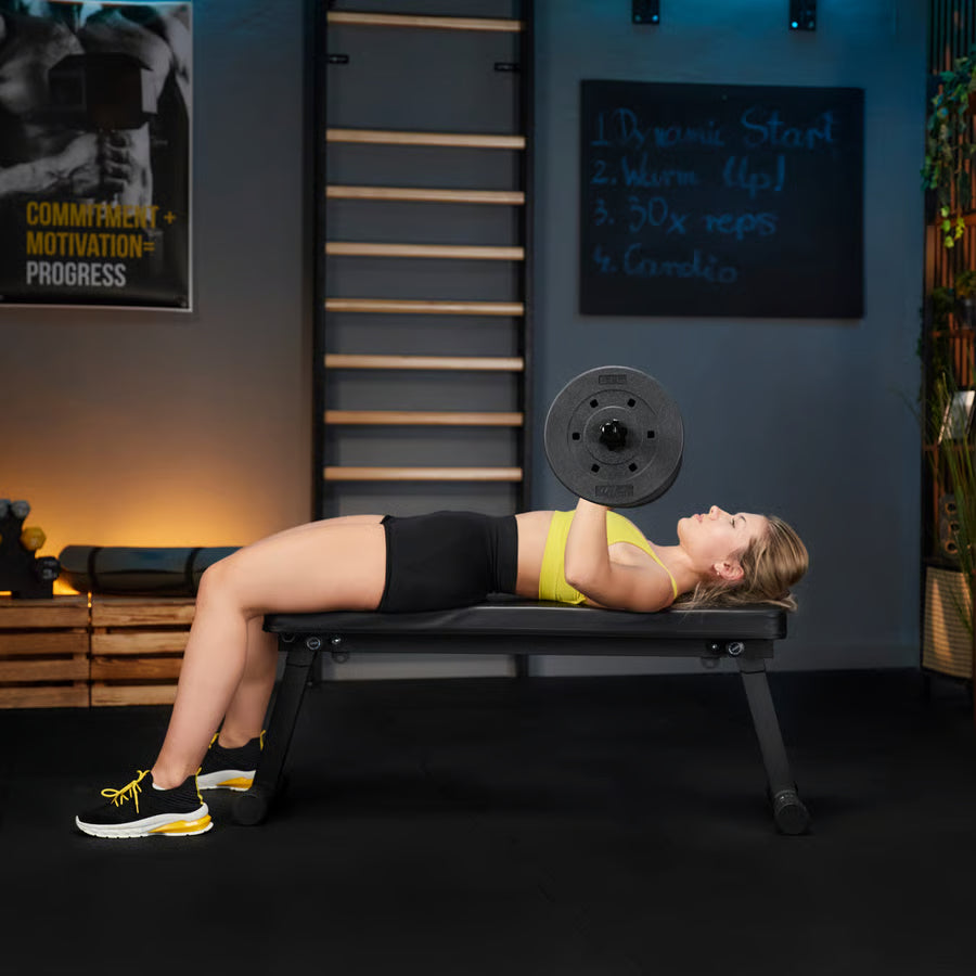 Woman performing a bench press with weights in a gym setting.