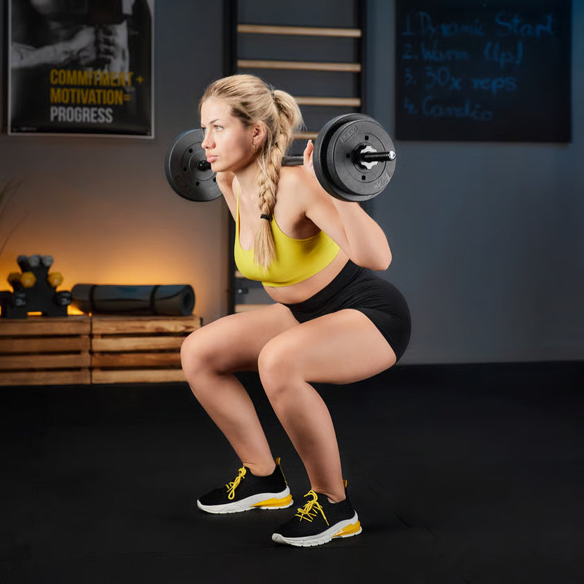 Woman performing squats with a barbell in a gym setting