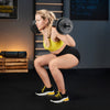 Woman performing squats with dumbbells in a gym setting